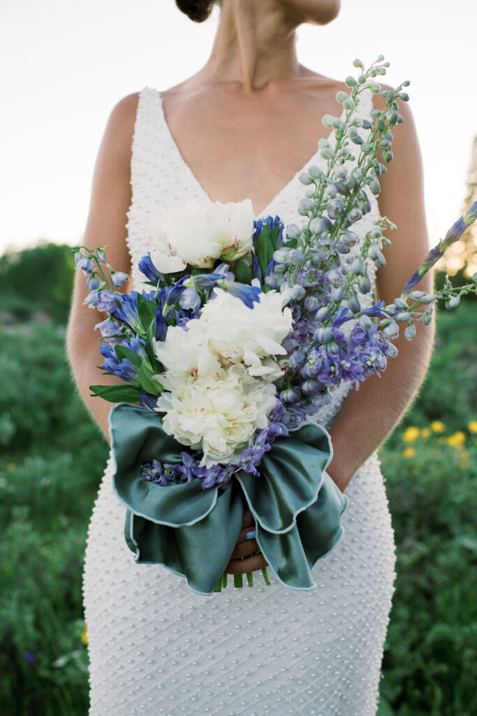 Detail photo of a brides bouquet that is white, blue, and purple 