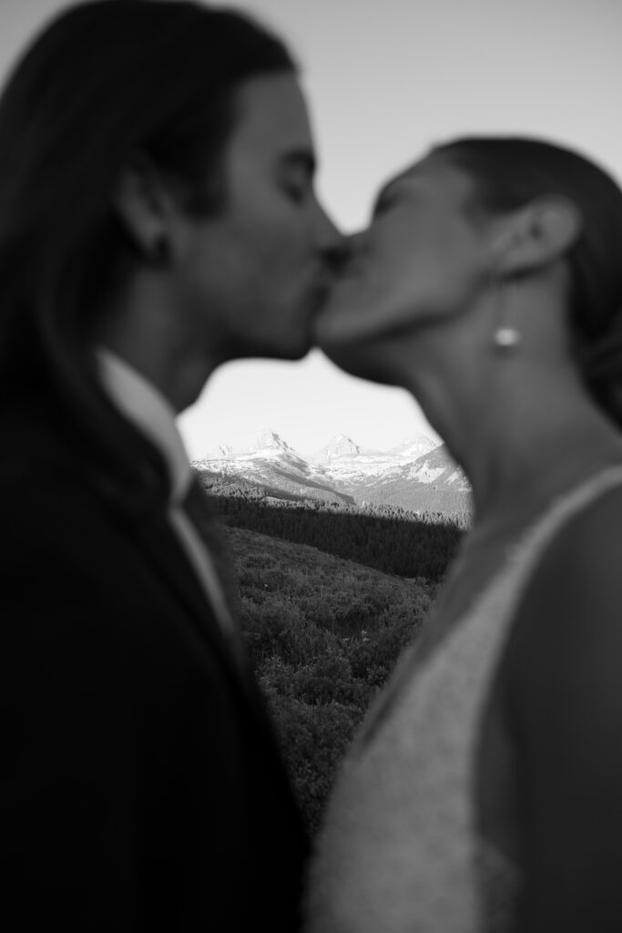 Couple kissing, in black and white with the Grand Teton National Park in the distance 