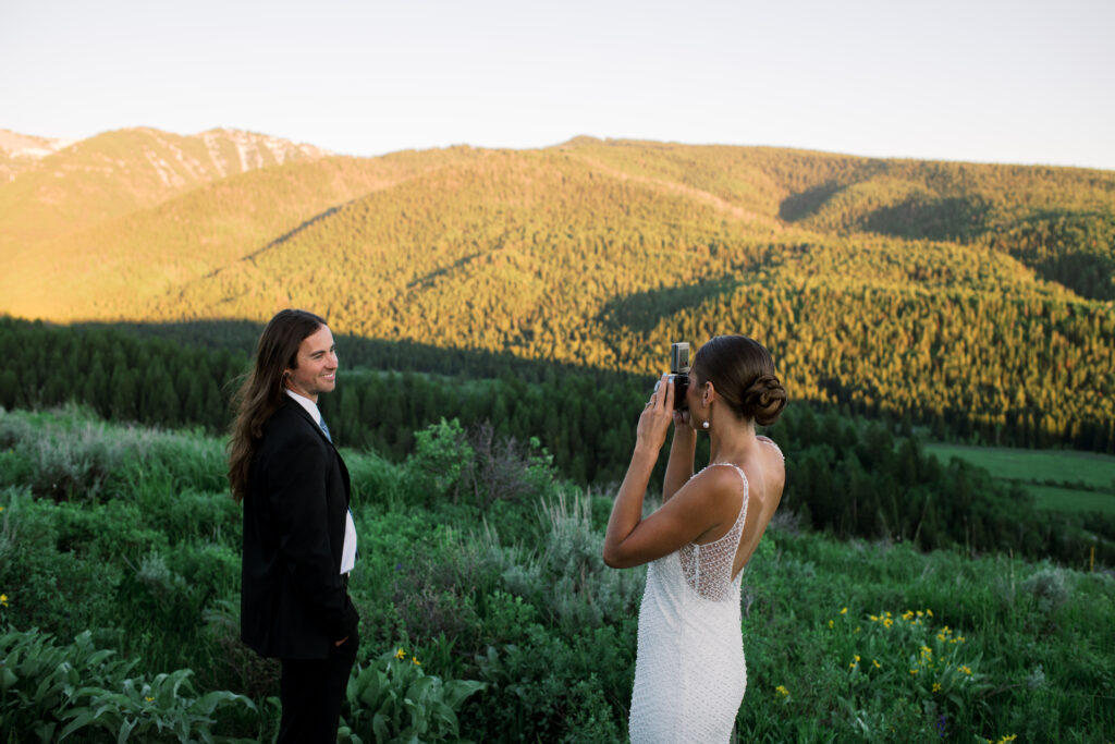 Bride taking a photo of groom with a film camera 