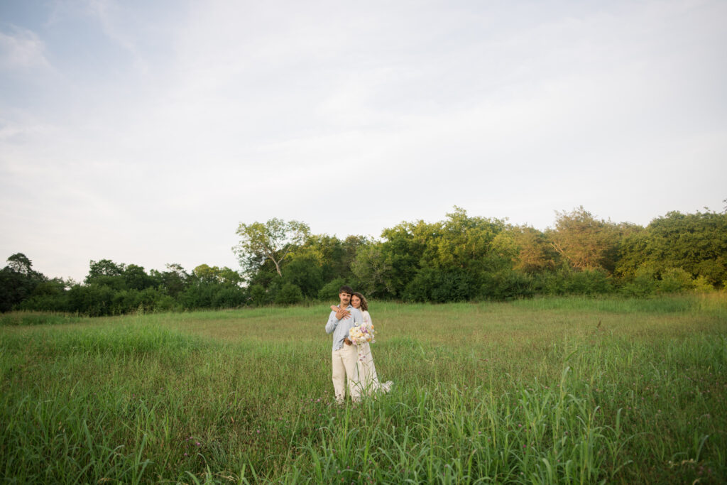 Bride and groom smiling at the camera while posing for a traditional wedding portraits 