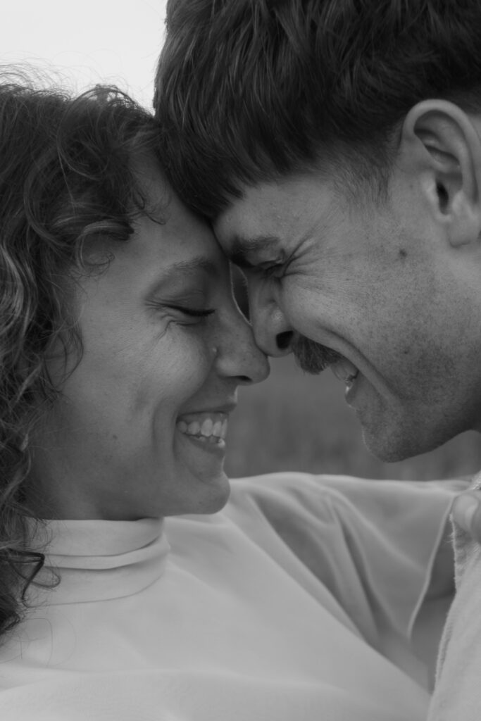 Up close photo of bride and groom smiling at each other in black and white on their wedding day