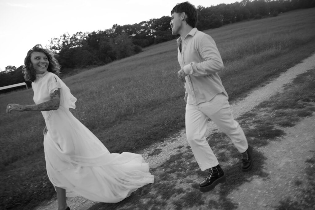 Couple running in a field on their wedding day 