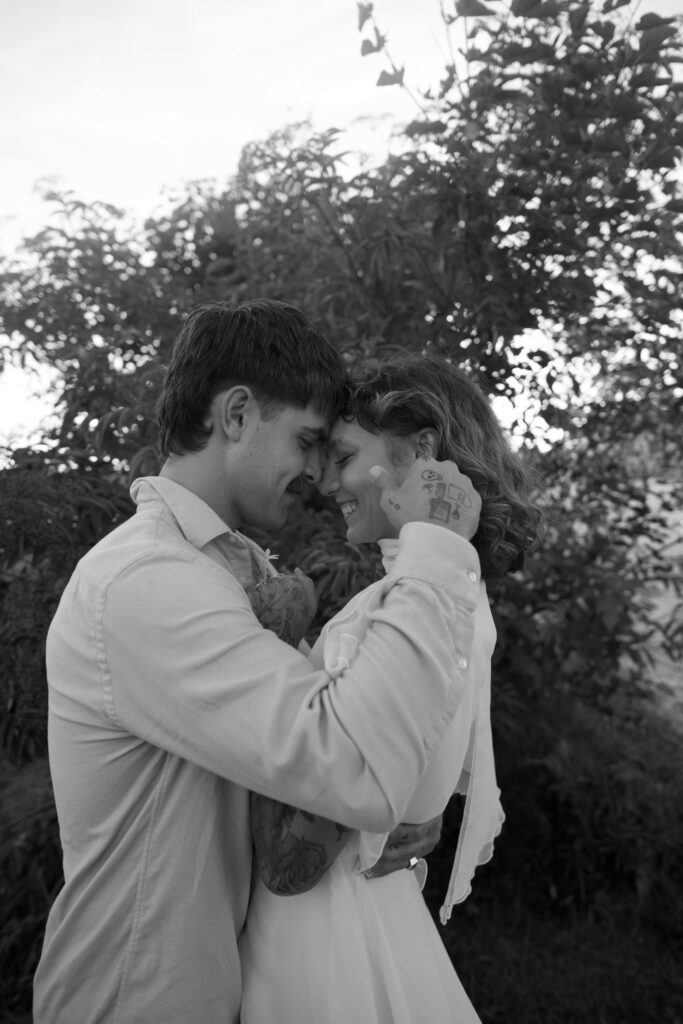 Bride and Groom embracing with faces together during wedding portraits in black and white 