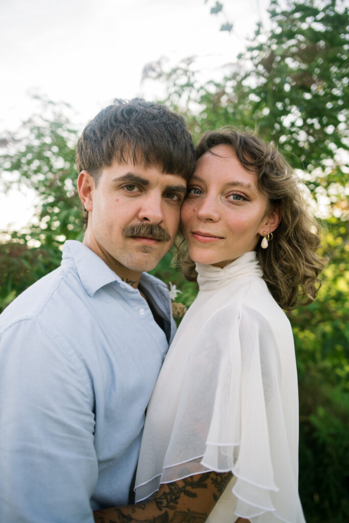 Bride and Groom looking directly into camera with faces together during wedding portraits 