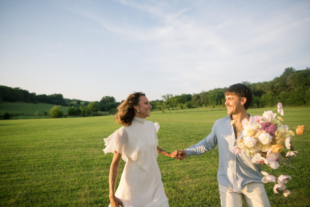 Couple running in a field on their wedding day 