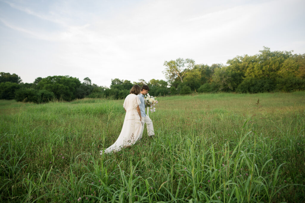 Couple walking into the middle of a pasture for wedding portraits 