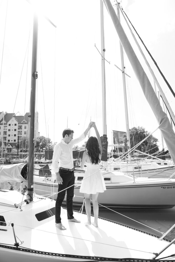 Couple posing for on their friends sailboat for their engagement photos in Louisville, Kentucky