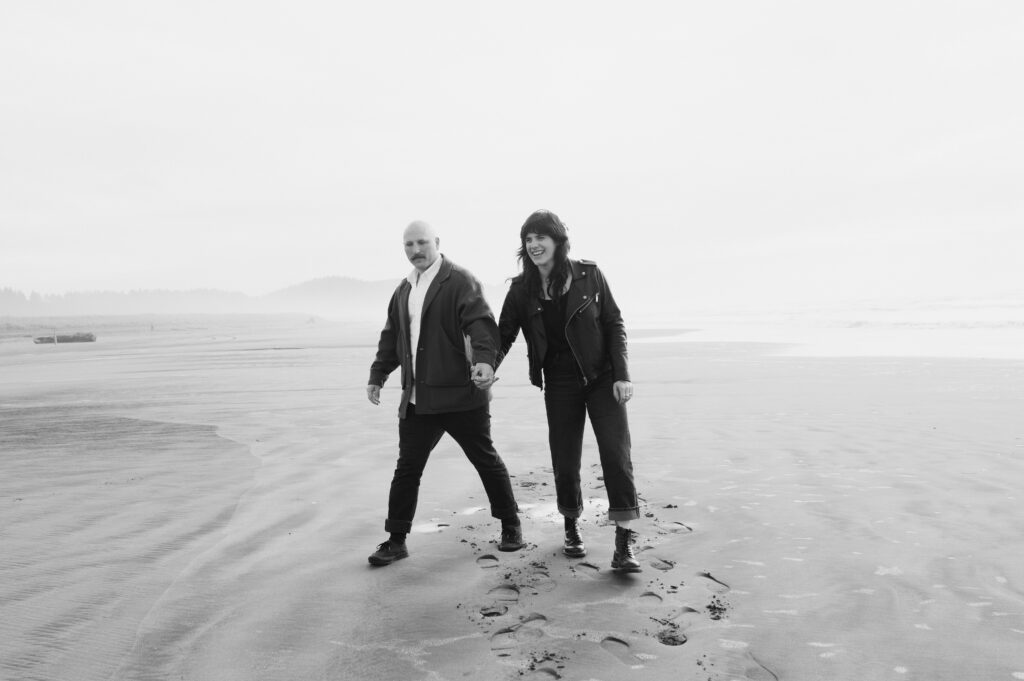 A couple walking toward the camera during their PNW Engagement session on the coast in Seaview, Washington