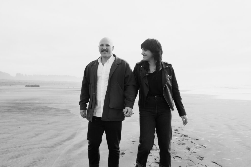 A couple walking toward the camera during their PNW Engagement session on the coast in Seaview, Washington