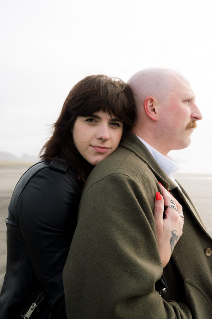 A couple looking toward the camera during their PNW Engagement session on the coast in Seaview, Washington