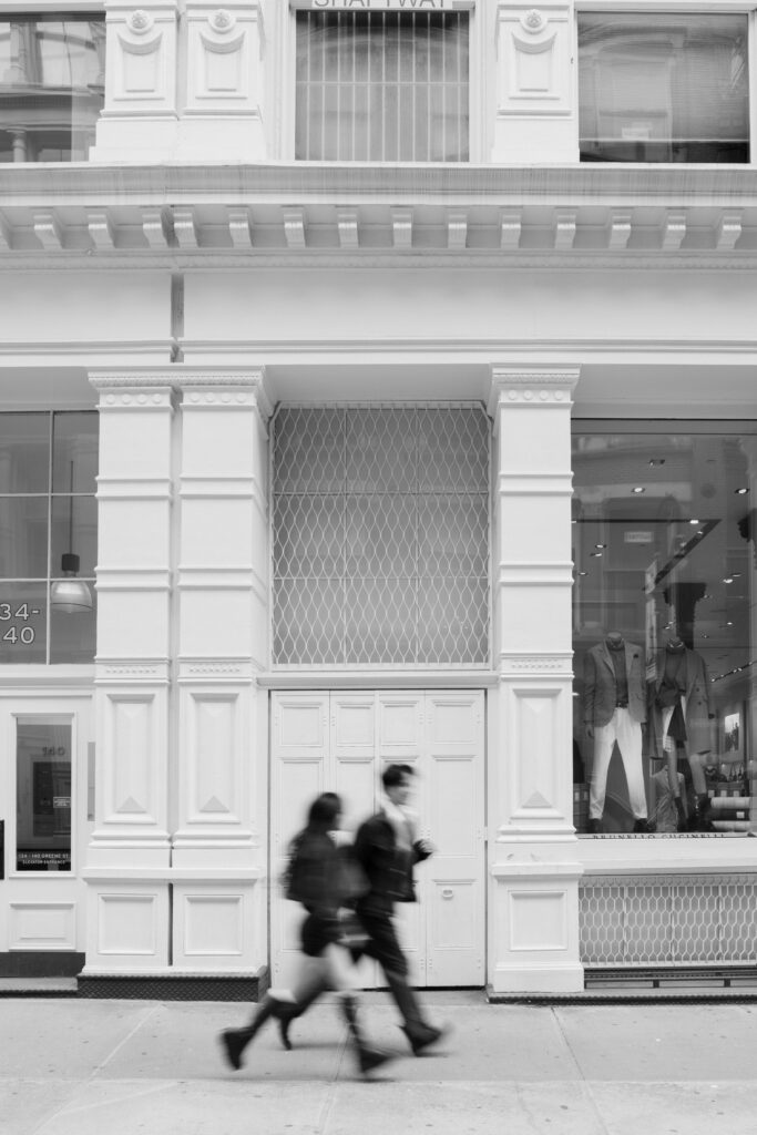 Black and white image of couple running down the street in Soho, NYC