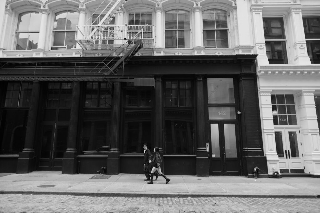 Black and white image of couple running down the street in Soho, NYC