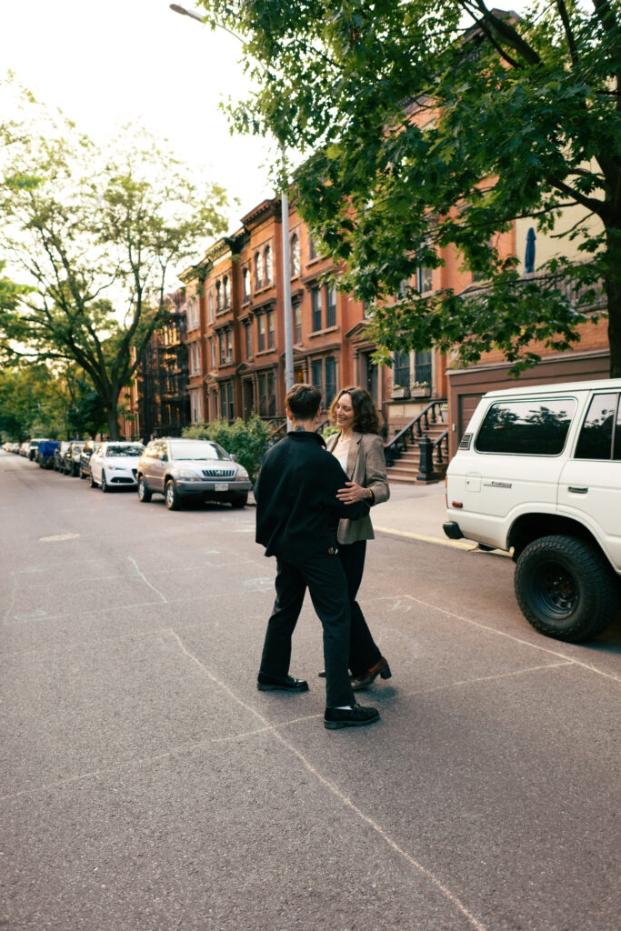 Couple dancing with a vintage Land Cruiser behind them in Brooklyn, New York during their engagement session