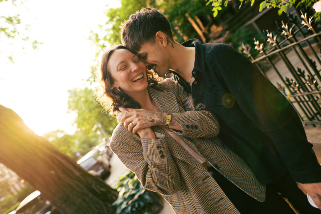 Photo of couple walking down the street with their arms around each other, laughing, during their Brooklyn  engagement session 