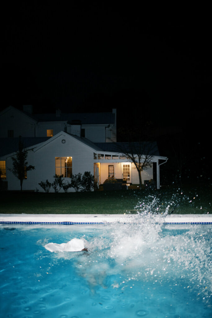 Bride and groom jumping in the pool atthe end of their wedding night
