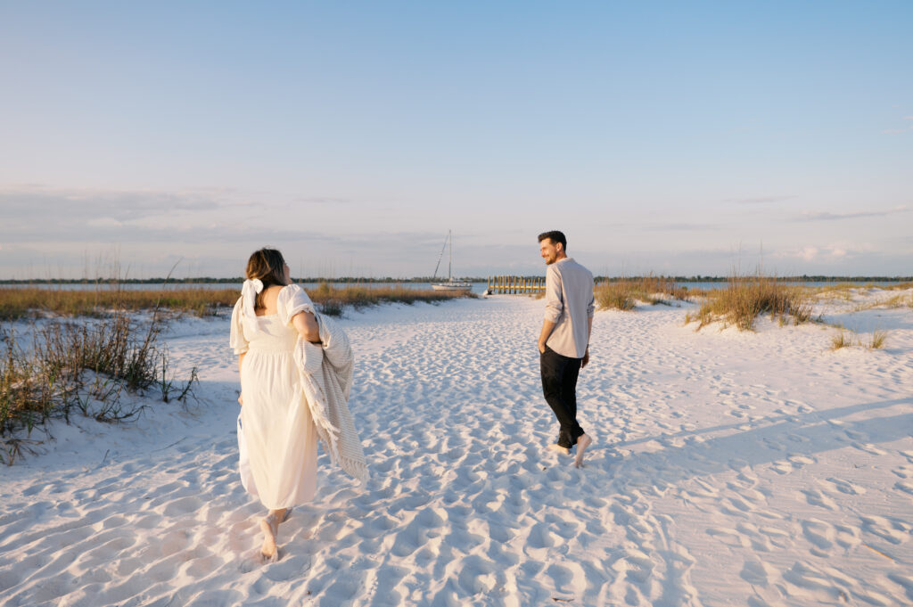 A couple snuggled in a blanket on the coast in Wilmington, North Carolina for their engagement sesion