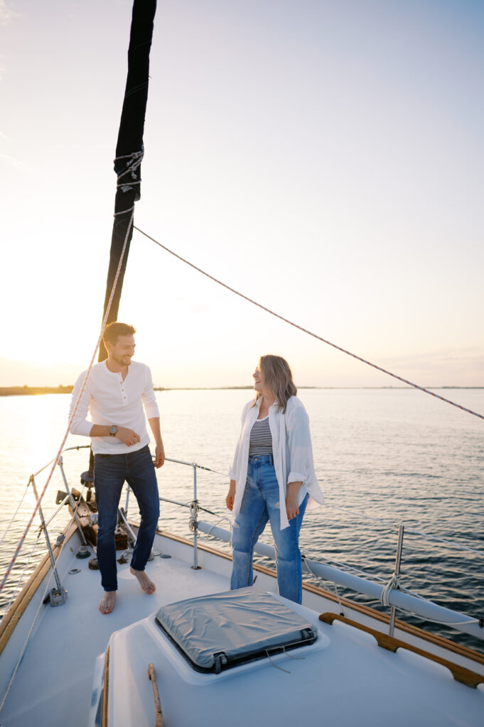 A couple posing on their sailboat for their engagement photos off the coast in Wilmington, North Carolina