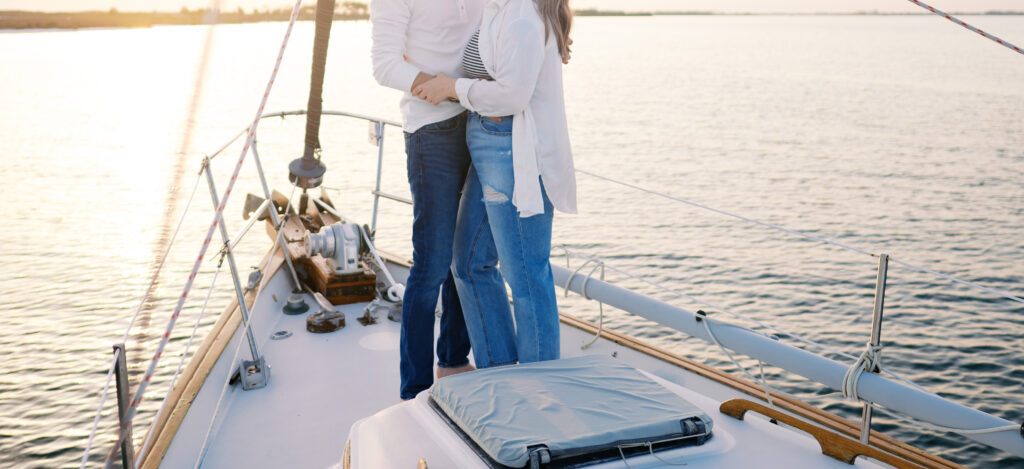 A couple posing on their sailboat for their engagement photos off the coast in Wilmington, North Carolina
