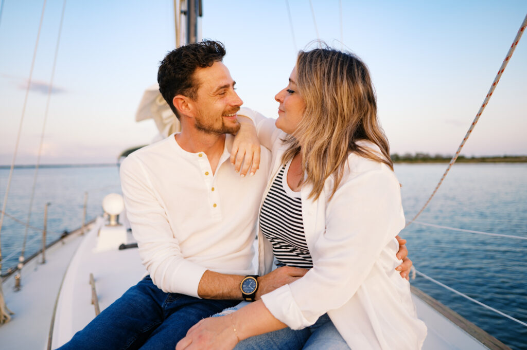 A couple posing on their sailboat for their engagement photos off the coast in Wilmington, North Carolina