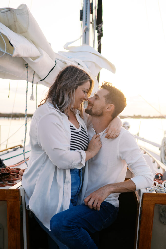 A couple posing on their sailboat for their engagement photos off the coast in Wilmington, North Carolina