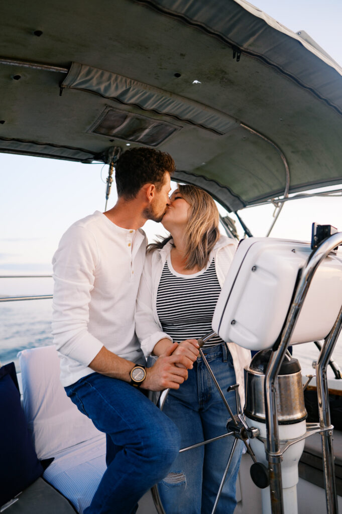 A couple kissing on their sailboat for their engagement photos off the coast in Wilmington, North Carolina
