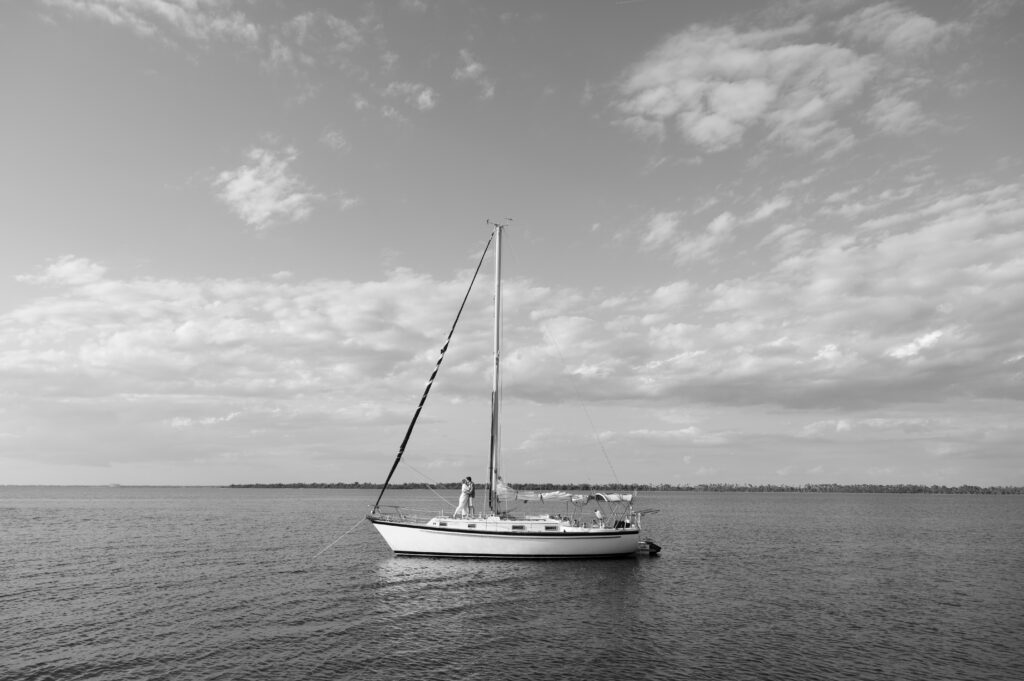Black and white image of a sailboat with a couple kissing on it in Wilmington, North Carolina