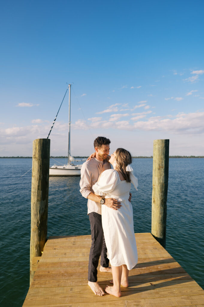 Photo of a couple looking at either other in Wilmington, North Carolina at their engagement session on a dock on the coast