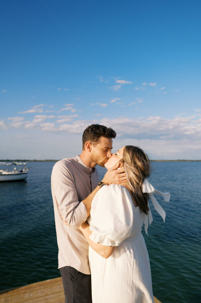 Photo of a couple kissing each either other in Wilmington, North Carolina at their engagement session on a dock on the coast
