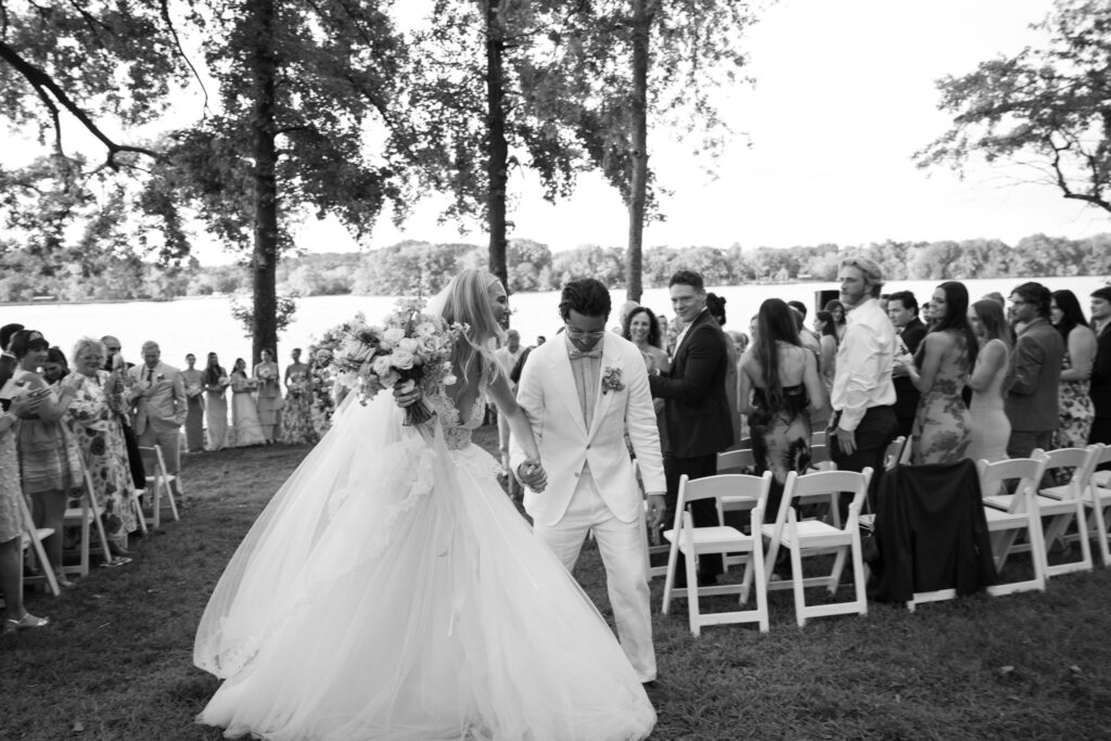 A black and white image of a couple walking down the aisle after their wedding ceremony