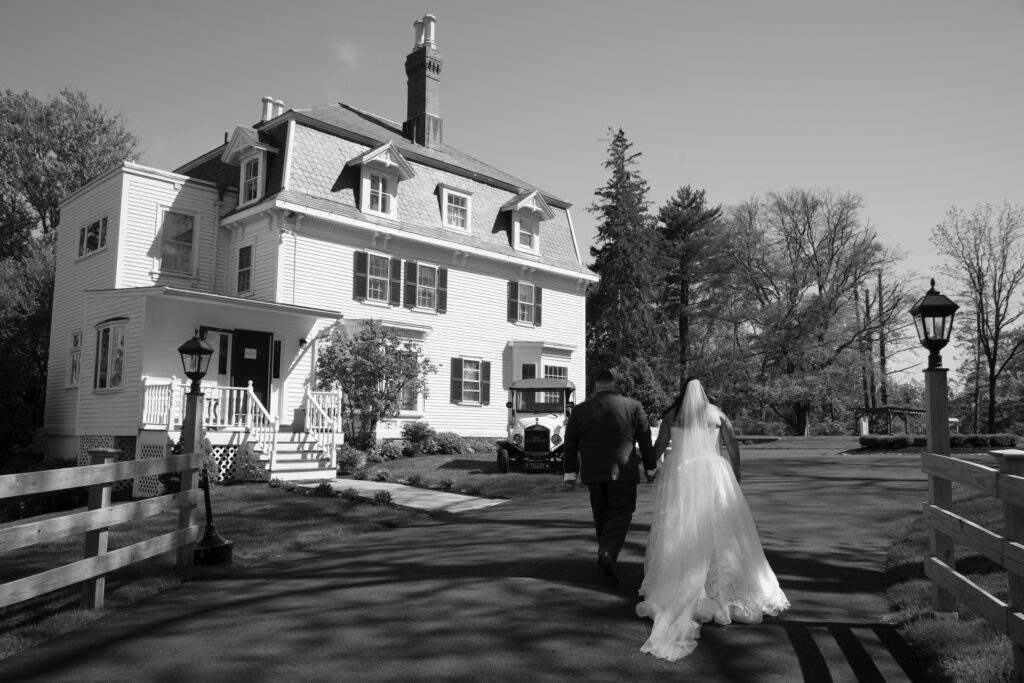 Black and white image of a couple walking to their venue by Wilmington Wedding Photographer Bri Nicole Photo Co.